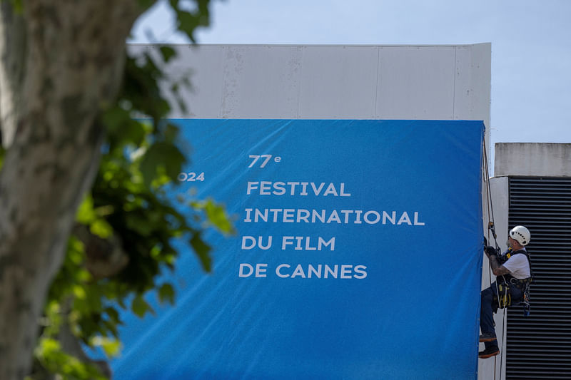 A worker sets up a large canvas of the 77th Cannes Film Festival official poster, which pays tribute to Japanese master filmmaker Akira Kurosawa and his late career feature 'Rhapsody in August', on the facade of the festival palace ahead of the festival's opening ceremony, in Cannes, France, 12 May, 2024.