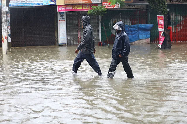 Two people walk along a waterlogged at Shibganj on Monday.