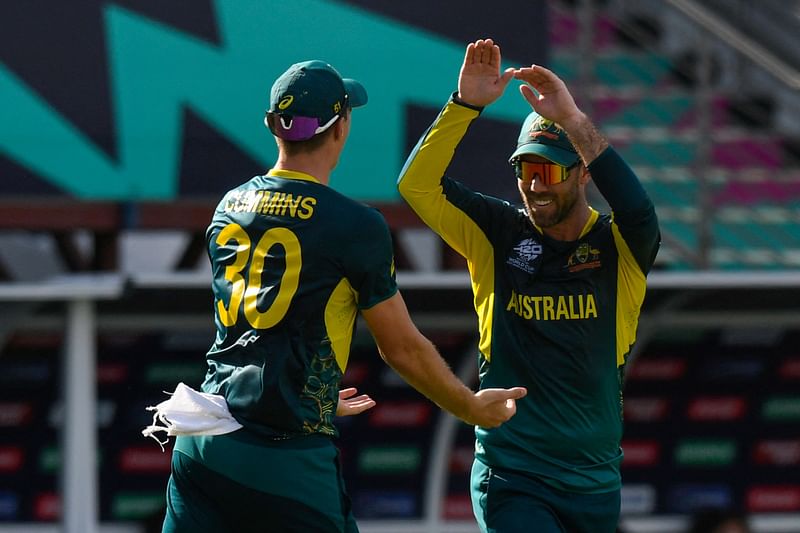 Australia's Glenn Maxwell (R) and Australia's Pat Cummins celebrate the dismissal of England's Jonathan Bairstow during the ICC men's Twenty20 World Cup 2024 group B cricket match at Kensington Oval in Bridgetown, Barbados, on 8 June, 2024.