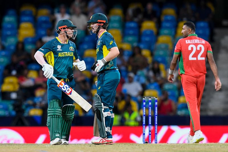 Oman’s Kaleemullah (R) looks on as he walks by Australia’s David Warner (L) and Travis Head (C) during the ICC men’s Twenty20 World Cup 2024 group B cricket match between Australia and Oman at Kensington Oval in Bridgetown, Barbados, on 5 June, 2024