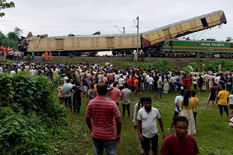 People look on at the site of a collision between an express passenger train and a goods train in Nirmaljote, near Rangapani station in India's West Bangal state on 17 June, 2024.