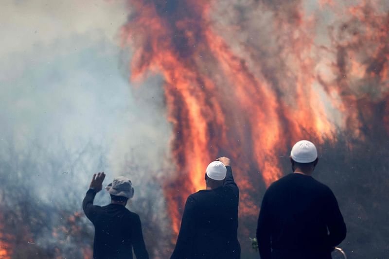 Local Druze men watch the flames burning a field after rockets launched from southern Lebanon landed on the Banias area in the Israel-annexed Golan Heights on 9 June, 2024.