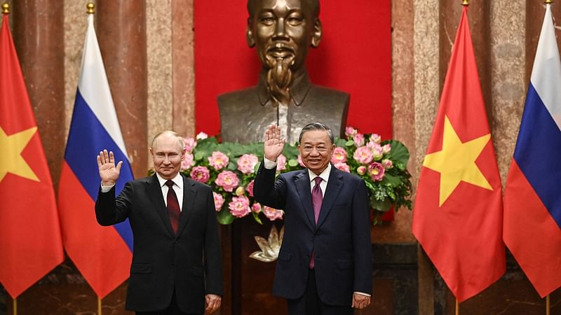 Russia's President Vladimir Putin (L) and Vietnam's President To Lam (R) wave as they pose for photos at the Presidential Palace in Hanoi on 20 June, 2024.