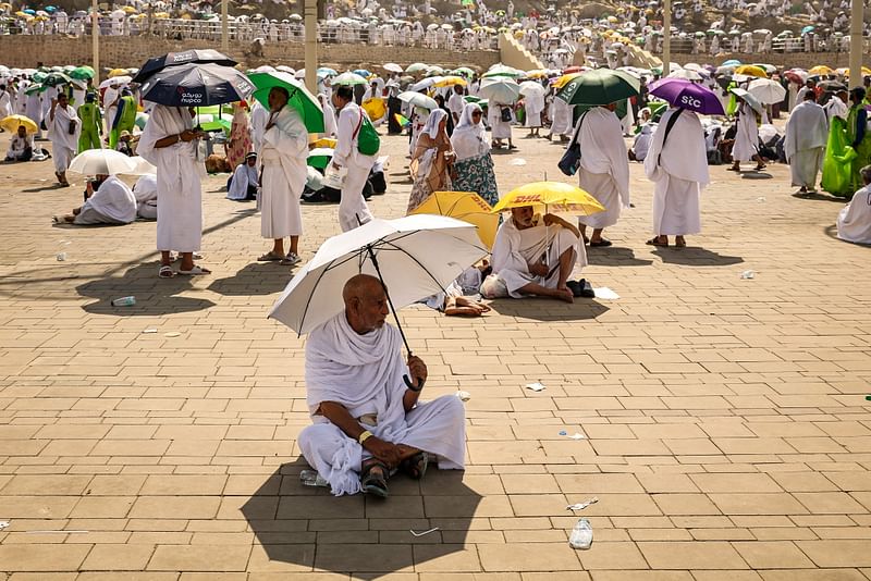 Muslim pilgrims use umbrellas to shade themselves from the sun as they arrive at the base of Mount Arafat, also known as Jabal al-Rahma or Mount of Mercy, during the annual hajj pilgrimage on 15 June 2024.