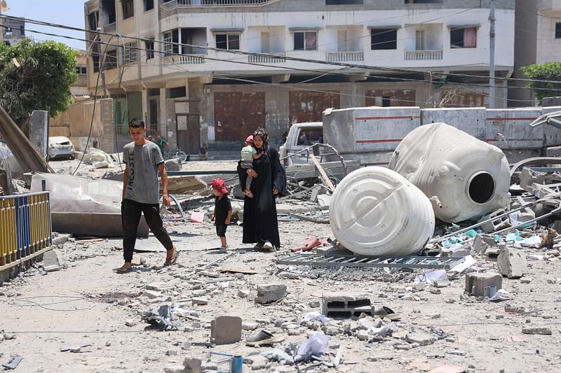 People walk next to rubble on grounds of the damaged headquarters of the United Nations Relief and Works Agency for Palestine Refugees (UNRWA) in Gaza City on 23 June, 2024, amid the ongoing battle between Israel and the Palestinian militant group Hamas