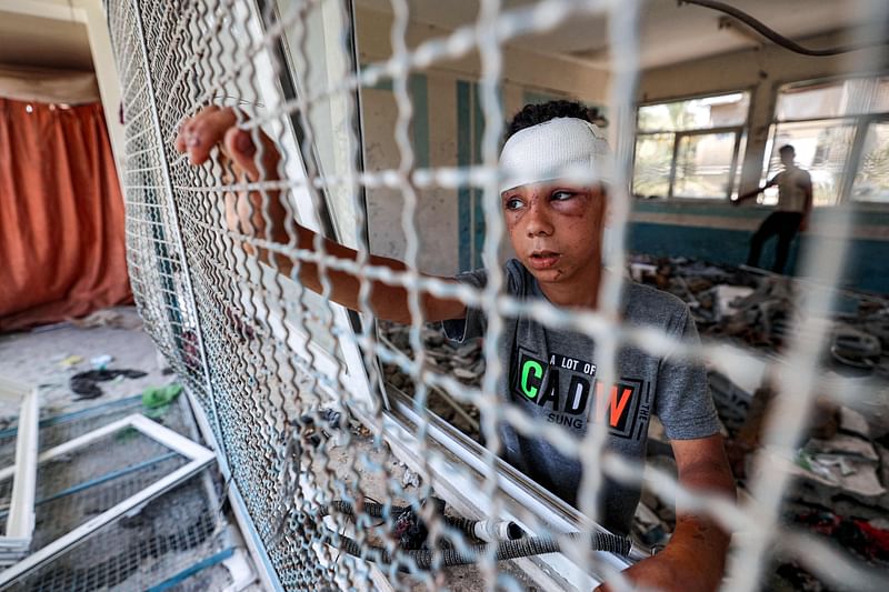 An injured boy stands by a window lattice in a destroyed classroom where people were sheltering at a school run by the UN Relief and Works Agency for Palestine Refugees (UNRWA) that was previously hit by Israeli bombardment, in the Nuseirat camp in the central Gaza Strip on June 7, 2024 amid the ongoing conflict in the Palestinian territory between Israel and Hamas.