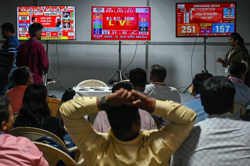 Journalists watch as election results on a television screen in a media room set up outside an election vote counting centre in Mumbai on 4 June 2024.