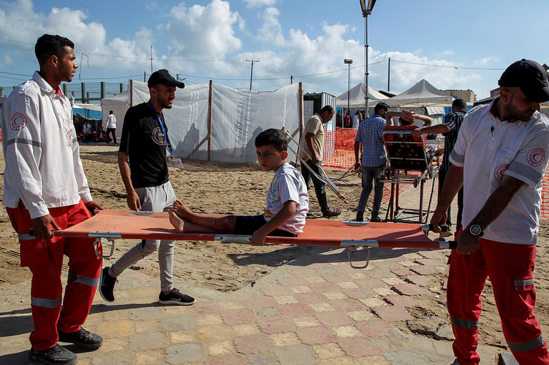 Paramedics carry a Palestinian boy wounded in an Israeli strike, at a field hospital in Rafah in the southern Gaza Strip, 30 May 2024.