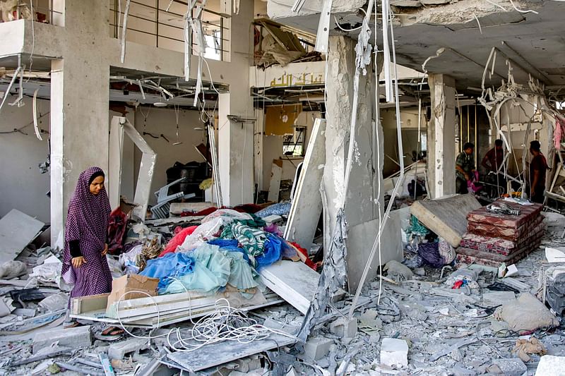 A woman sorts through clothing salvaged from the rubble of a destroyed dress shop in a residential building hit by Israeli bombardment, in the Daraj neighbourhood in Gaza City on 14 June, 2024, amid the ongoing conflict between Israel and Hamas