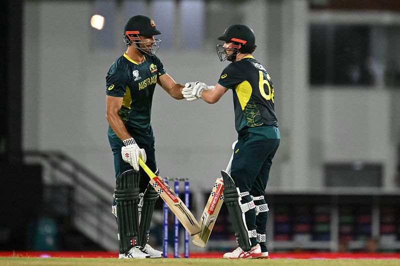 Travis Head (R) bumps fists with Australia's Marcus Stoinis during the group B cricket match between Australia and Scotland at Daren Sammy Cricket Ground in Gros Islet, St. Lucia, on 15 June, 2024.