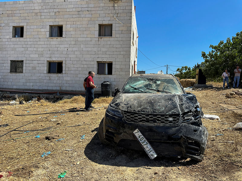 People check the damage of a car targeted by Israeli forces during a raid in which Palestinians were killed, near Ramallah, in the Israeli-occupied West Bank on 11 June, 2024