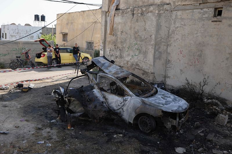 Graphic content / Palestinian men look at a burnt car after a raid by Israeli forces in the village of Kfar Dan, east of Jenin in the occupied West Bank on 12 June, 2024