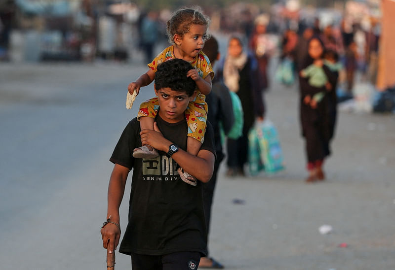 A Palestinian adolescent boy carries a child on his shoulders as they flee Rafah due to an Israeli military operation, amid the Israel-Hamas conflict, in Rafah, in the southern Gaza Strip, on 7 June, 2024