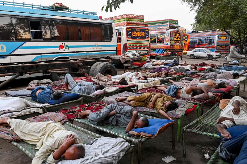 Drivers sleep at a bus station on a hot summer day in Lahore on 2 June, 2024, amid severe heatwave.