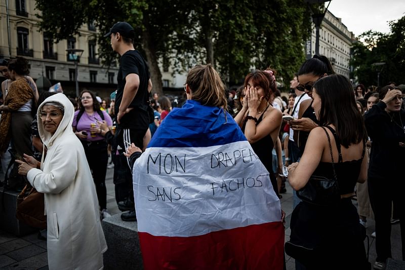 Left wing supporters celebrate - one with a Franch tricolor with the message which translates as ' my flag without Facists' - during a rally after the announcement of the projected results of the second round of France's parliamentary elections in Lyon, eastern France on 7 July 2024.