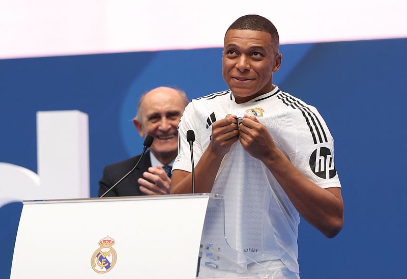 French forward Kylian Mbappe (R) greets fans next to the Honorary President of the Real Madrid Jose Martinez Pirri during his first appearance as a Real Madrid player at the Santiago Bernabeu Stadium in Madrid on 16 July, 2024, after signing his new five-season contract. Still celebrating Spain’s Euro 2024 triumph, Real Madrid fans have even more to cheer this July 16, 2024, as French superstar Kylian Mbappe is officially presented to a packed-out Santiago Bernabeu stadium