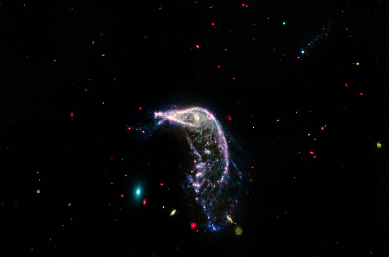 Arp 142, two interacting galaxies, are shown in an image obtained by the James Webb Space Telescope, using its Mid-Infrared Instrument (MIRI) instrument, released by NASA on 12 July, 2014. At left is NGC 2937, an elliptical galaxy that looks like a tiny teal oval and is nicknamed the Egg. At right is NGC 2936, a distorted spiral galaxy nicknamed the Penguin, which is significantly larger.