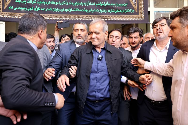 Iranian reformist presidential candidate Masoud Pezeshkian (C) leaves a polling station after voting in Tehran on 5 July 2024.