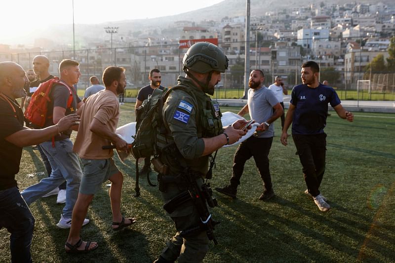 Israeli security forces and medics transport casualties from a site where a reported strike from Lebanon fell in Majdal Shams village in the Israeli-annexed Golan area on 27 July, 2024. Israel's emergency medical service Magen David Adom said at least nine people were killed and 34 wounded including 17 in critical condition, after a rocket fired from Lebanon had hit the town of Majdal Shams in the Israeli-annexed Golan Heights.