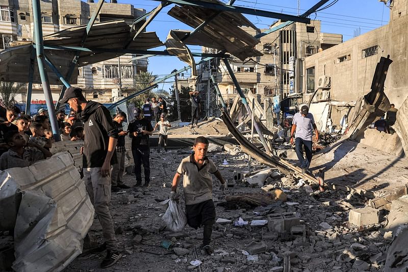 A boy runs with a sack as people search the rubble of a collapsed building in the aftermath of Israeli bombardment at the Jaouni school run by the UN Relief and Works Agency for Palestine Refugees (UNRWA) in Nuseirat in the central Gaza Strip on on 6 July, 2024.