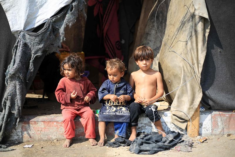 Displaced Palestinian children sit in front of a tent used as temporary shelter in Deir el-Balah in the central Gaza Strip on 7 July 2024.