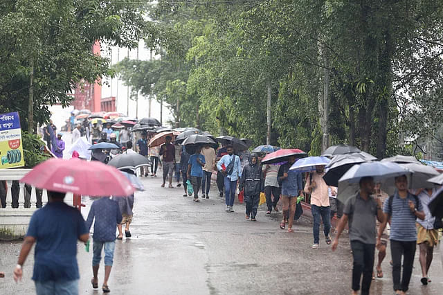 People carrying umbrellas on the way to work in the rain in Sylhet city at Kin Bridge on Monday morning.