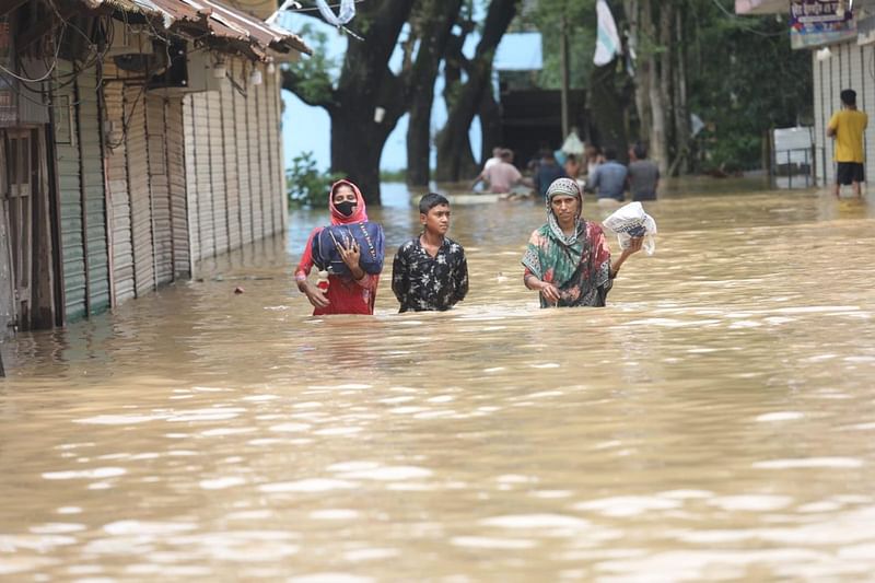 People wade through waist-deep water in the Samitee Bazar area of Nijkunjora village of 10 number Ghopal union of Chhagalnaiya upazila in Feni on 23 August 2024 as heavy rain and water from upstream inundates the entire area of Chhagalnaiya upazila.