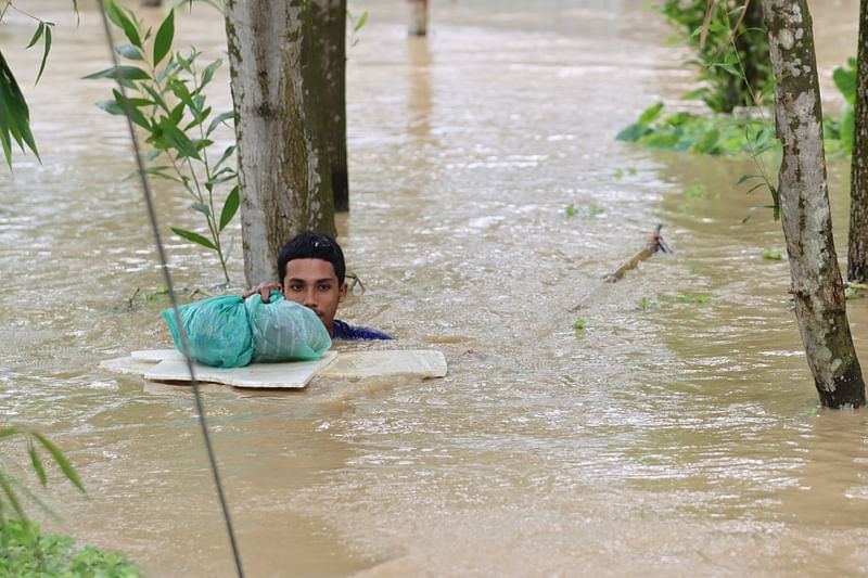 A boy wades through neck-deep water in search of a shelter after heavy rainfalls and water from upstream breaks embankment on Gomti river in Burburi area of Sholonal union in Burichang upazila of Cumilla, inundating the entire area. The picture was taken on 23 August 2024.