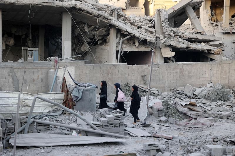 Palestinian women walk amid the rubble in the vicinity of a building shortly after it was levelled by Israeli bombing in the Nuseirat refugee camp in the central Gaza Strip on 22 August, 2024