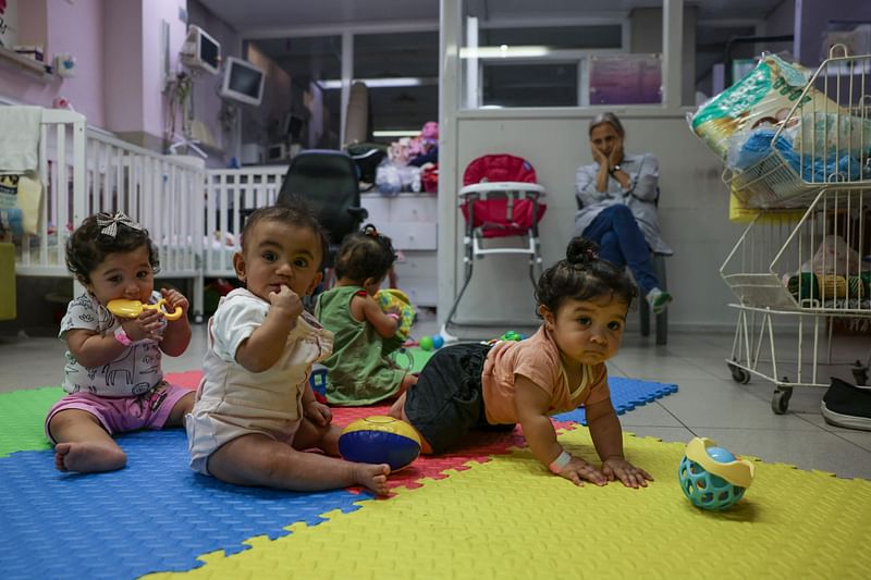 Palestinian triplets of Gaza-native Hanane Bayouk, Najmeh (L), Noor (C)and Najoua play with another toddler, at the children's ward of the Al-Maqased Hospital in east Jerusalem on 31 July, 2024. The triplets were born at the Al-Maqased Hospital where the mother came from the Gaza Strip to give birth, returning soon after when her travel permit issued by Israel expired, leaving her babies in their care. After arriving in Gaza, the 7 October attacks by the militant Palestinian group Hamas on southern Israel took place, and their mother has been stuck in the Gaza Strip since then.