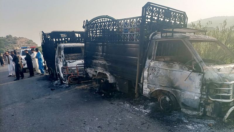 Security personnel stand near the charred vehicles at the shooting site on the national highway in Musakhail district, Balochistan province on 26 August, 2024