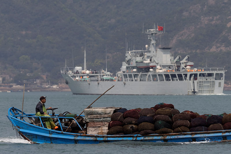 A fishing boat sails past a Chinese warship during a military drill off the Chinese coast near Fuzhou, Fujian Province, across from the Taiwan-controlled Matsu Islands, China, 11 April 2023.