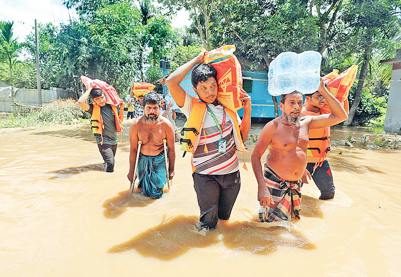 Locals and volunteers carry relief items to the nearby Neyamatpur Government Primary School shelter centre on 28 August 2024.