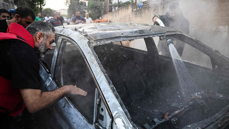 A firefighter extinguishes the flames of a smouldering car in the small town of Zababdeh, southeast of Jenin in the occupied West Bank on 30 August, 2024, following an Israeli army raid