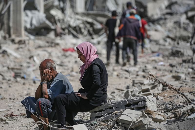 A Palestinian man who retuned briefly to eastern Deir al-Balah in central Gaza Strip to check on his home, reacts at the sight of the devastation as he sits next to a woman amid the rubble, after Israeli troops pulled out from some blocks in the area in August, 2024, amid the ongoing conflict between Israel and the Hamas militant group.