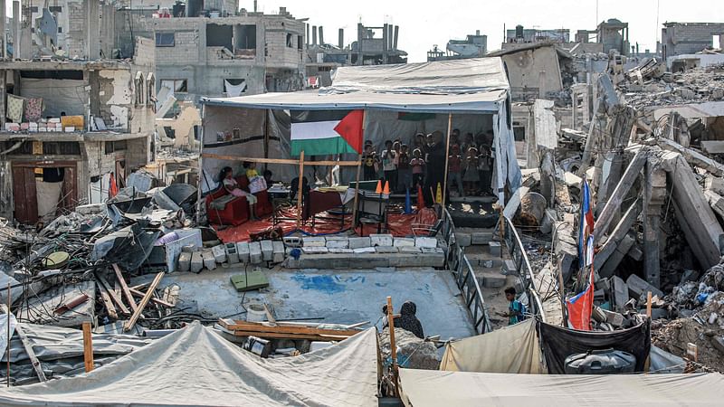 Children attend a class given by Palestinian teacher Israa Abu Mustafa (30), whose educational centre was destroyed during the ongoing war between Israel and Hamas, at a tent amidst the rubble of collapsed buildings in Khan Yunis in the southern Gaza Strip on 4 September, 2024