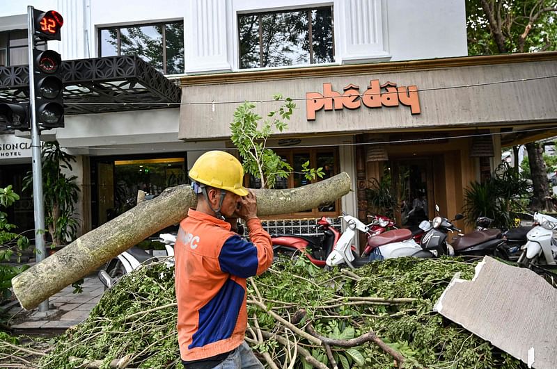 A worker removes the branch of a fallen tree branch on a street in Hanoi on 9 September, 2024, after Typhoon Yagi swept through northern Vietnam