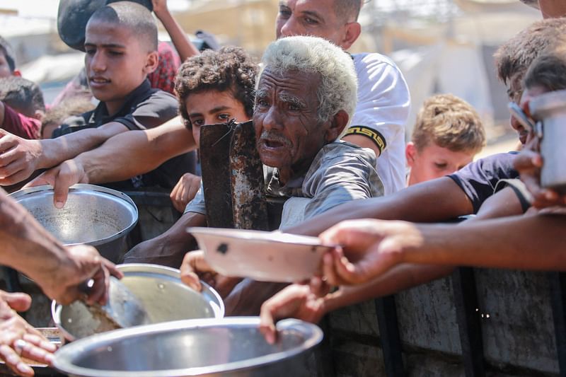 Palestinians receive cooked food rations as part of a volunteer initiative in a makeshift displacement camp in Mawasi Khan Yunis in the besieged Gaza Strip on 3 September 2024, amid the ongoing war between Israel and the Palestinian Hamas movement.