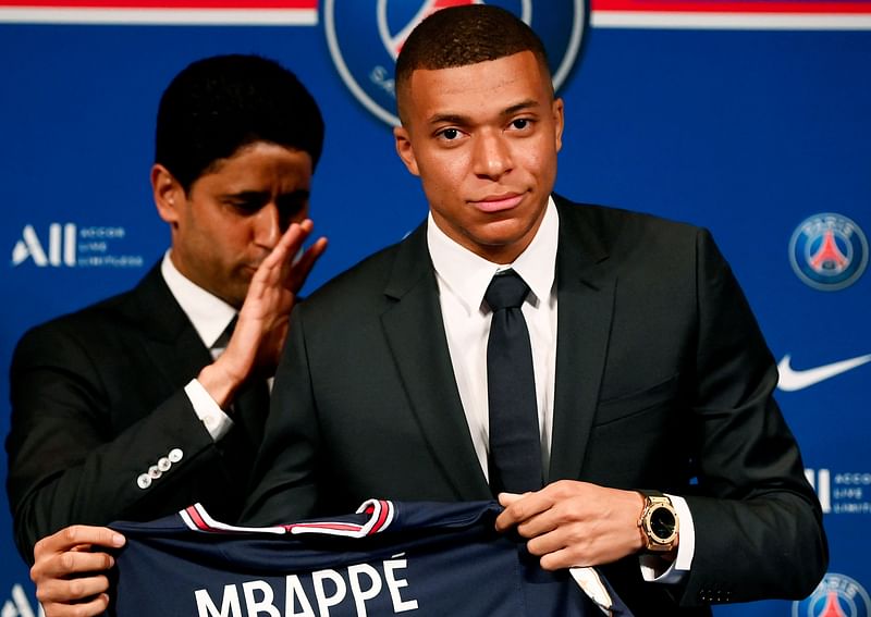 Paris Saint-Germain's CEO Nasser Al-Khelaifi (L) and French forward Kylian Mbappe (R) pose with a jersey at the end of a press conference at the Parc des Princes stadium in Paris on 23 May, 2022.