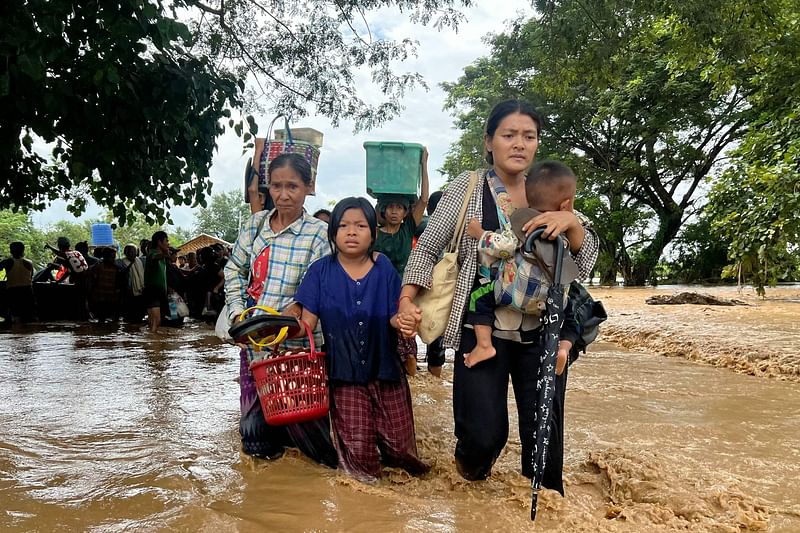 Residents walk through flood waters in Pyinmana in Myanmar's Naypyidaw region on 13 September, 2024, following heavy rains in the aftermath of Typhoon Yagi. Typhoon Yagi brought a colossal deluge of rain that has inundated a swathe of northern Vietnam, Laos, Thailand and Myanmar, triggering deadly landslides and widespread river flooding.