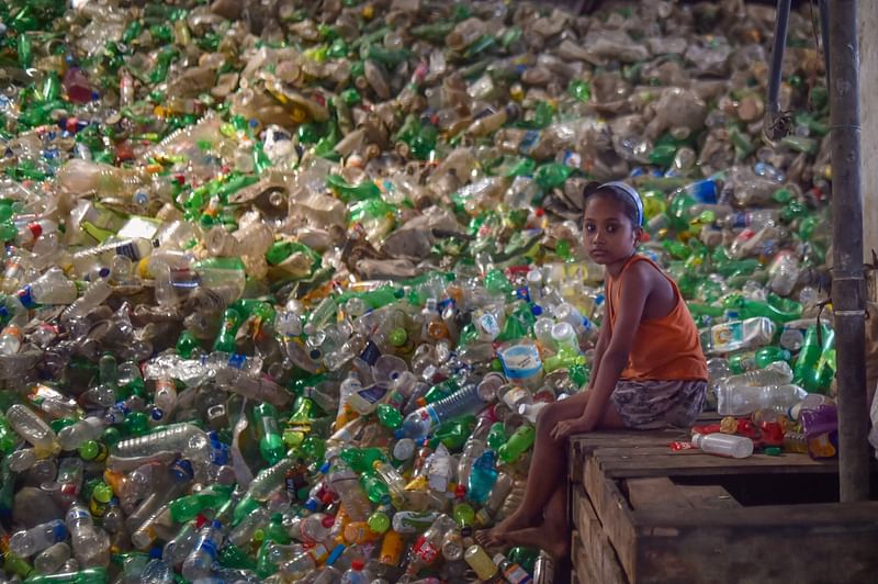 A girl looks on as she sits next to a pile of used plastic bottles in a recycling factory in Dhaka on 5 May, 2021. Global warming. Disappearing plant and animal species. Fertile land turning to desert. Plastic in the oceans, on land, and the air we breathe. These urgent environmental challenges will be in the spotlight over the next few months as the UN hosts four major sessions to address key threats to the planet.