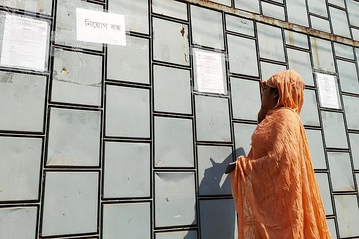 A garment worker reads the closure notice at the main gate of a RMG factory