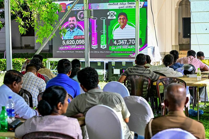 Members of National People's Power (NPP) party, watch presidential election results on a projected screen featuring NPP's presidential candidate Anura Kumara Dissanayaka (L) and Samagi Jana Balawegaya party's leader and presidential candidate Sajith Premadasa, at a counting centre in Colombo on 22 September 2024.