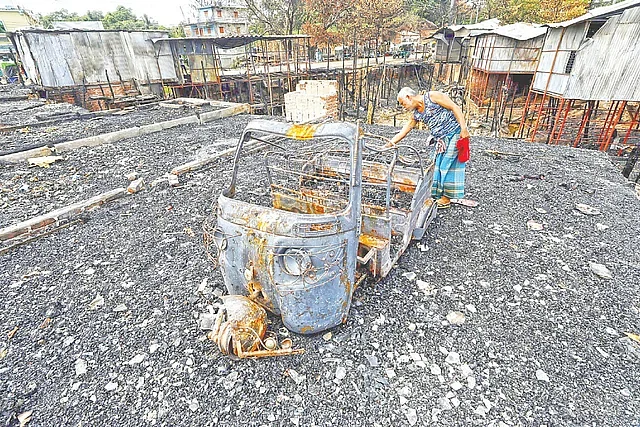 A man checking a burnt auto-rickshaw at Lama Square in Khagrachhari