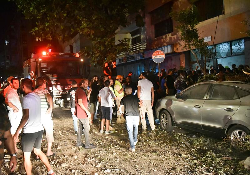 People gather outside an apartment building hit by an Israeli air strike in Beirut's Cola district, September 30, 2024.