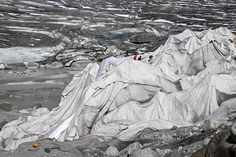 People work on some insulating fabric covering a small part of the Rhone Glacier to prevent it from melting, near Gletsch, in the Swiss Alps, on 30 September, 2024.