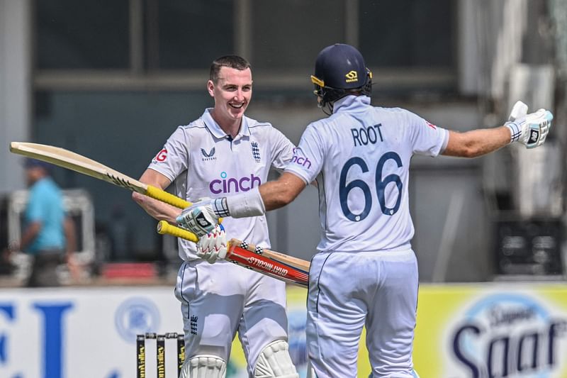 England's Harry Brook (L) celebrates with teammate Joe Root after scoring a double century (200 runs) during the fourth day of the first Test cricket match between Pakistan and England at the Multan Cricket Stadium in Multan on 10 October, 2024.