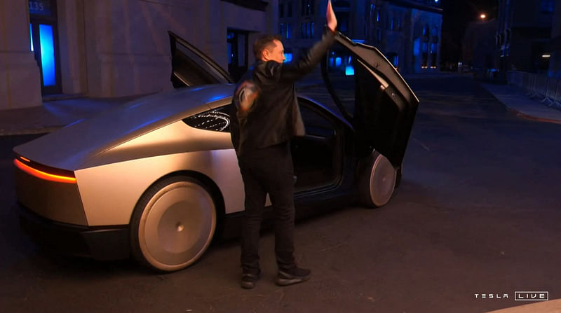 Video grab obtained 10 October, 2024 shows Tesla CEO Elon Musk waving next to his long-promised robotaxi during a launch event at the Warner Brothers studio lot near Los Angeles.