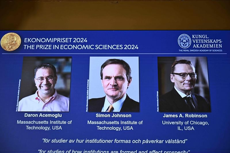 A screen shows the laureates (L-R) Turkish-American Daron Acemoglu and British-Americans Simon Johnson and James Robinson of the 2024 Sveriges Riksbank Prize in Economic Sciences in Memory of Alfred Nobel during the announcement by the Royal Swedish Academy of Sciences in Stockholm, Sweden on 14 October 2024.