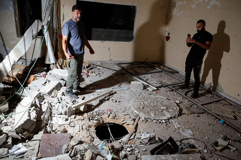 Palestinian men inspect damage inside a building in the aftermath of an Israeli raid in Jenin camp, in the Israeli-occupied West Bank, on 14 October 2024